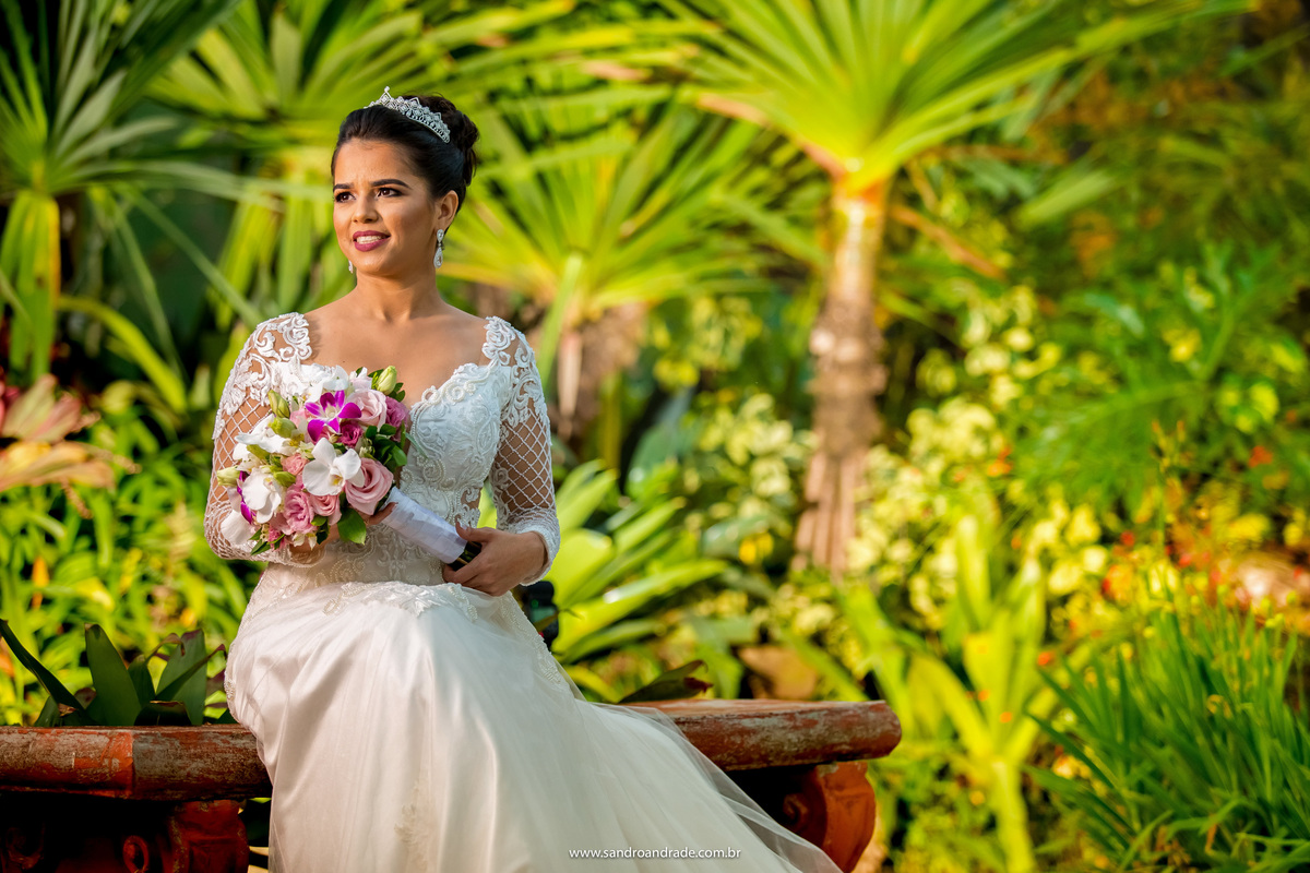 Retrato da noiva em cores vibrantes, muito verde de fundo e o colorido das orquídeas de seu buque.