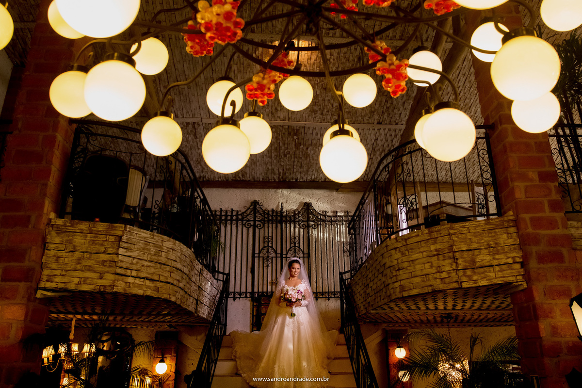 No mesmo lugar porem com um enquadramento diferente, Flavia esta na escada, de frente e o lustre está acima dela, fotografia com muita composição de um dos melhores fotógrafos de casamento do Brasil.