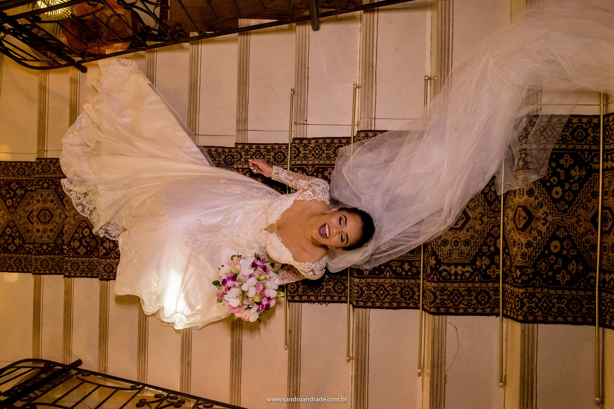 E para finalizar uma imagem cheia de alegria, Flavia está deitada na escadaria do salão de festas, sorrindo, muito feliz, uma linda imagem colorida e que nos deixa com gostinho de quero mais para as próximas fotos.