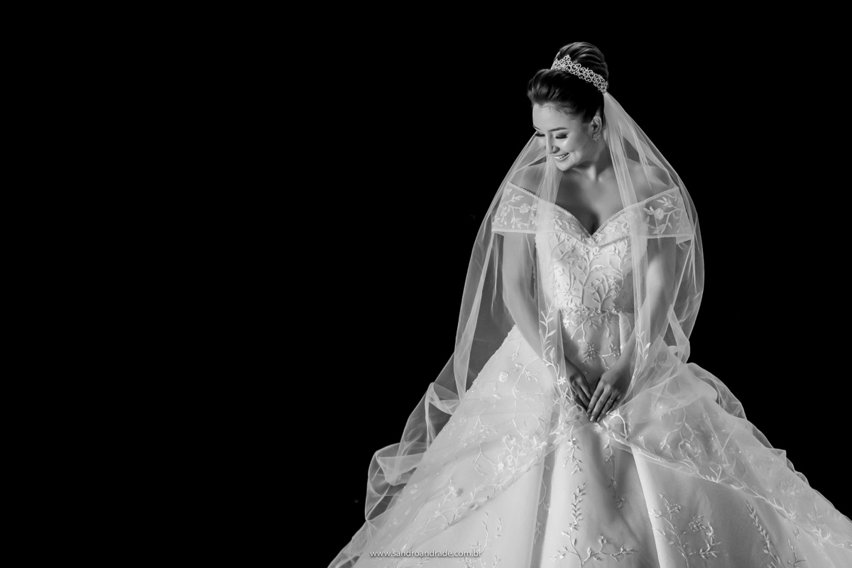 Um lindo retrato da noiva em preto e branco, finalizando nossa sessão de fotos antes da festa. Segurando seu véu , Dany olha lateral e sorri, em meio a um bréu, Sandro Andrade conseguiu esse lindo retrato.
