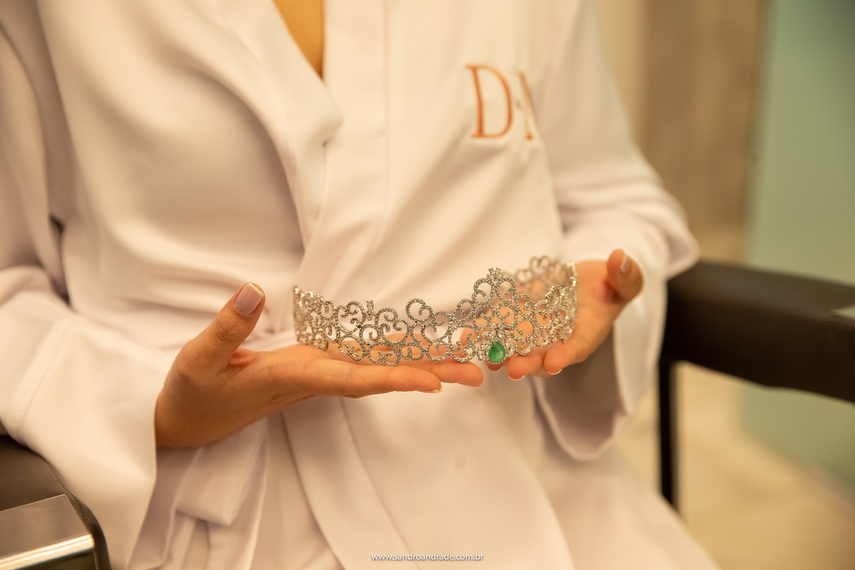 Aqui um detalhe, a noiva segurando sua linda coroa toda em cristais e com uma pedra verde ao centro.