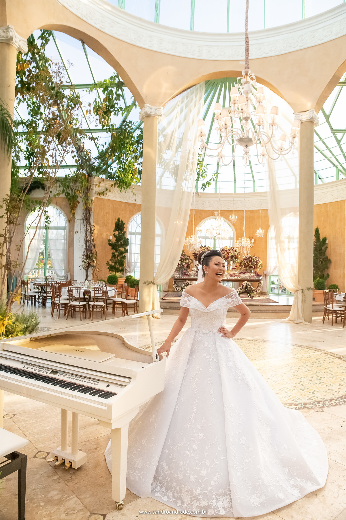 Dany sorri ao ver a linda surpresa que seu noivo preparou para ela, presente de casamento, um lindo piano de cauda branco, com um sorriso muito feliz e espontâneo.