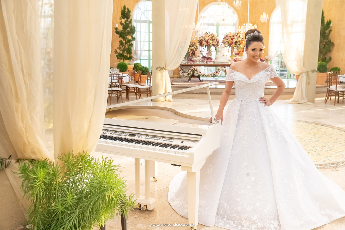 Posando para a foto ao lado de seu lindo piano de cauda branco, Dany está sorrindo. Uma linda fotografia colorida, dentro do pallazo da Villa Giardini, onde em alguns instantes começará sua festa de casamento. 