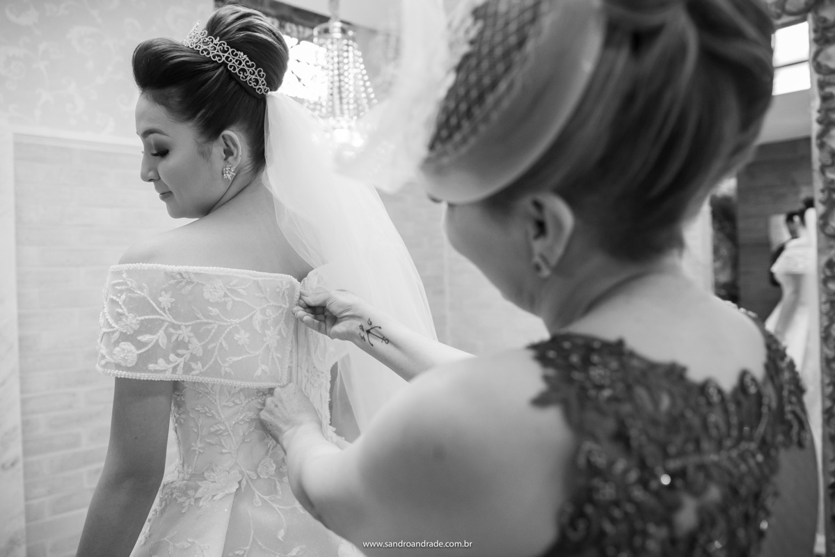 A mãe da noiva está fechando o belo vestido de noiva de sua filha.