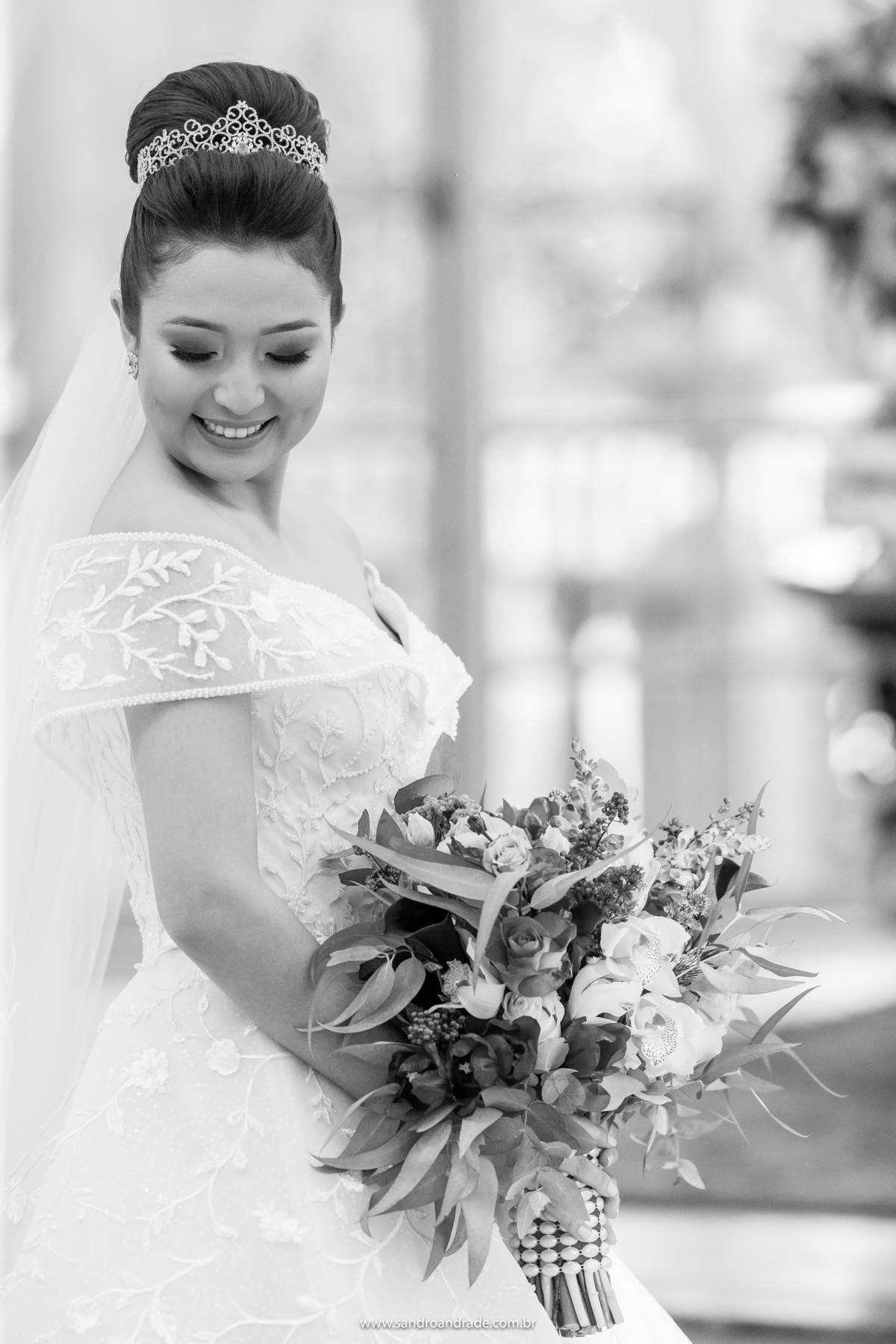 Retrato da noiva em preto e branco, de cabeça baixa, segurando seu lindo buque e de olhos fechados.