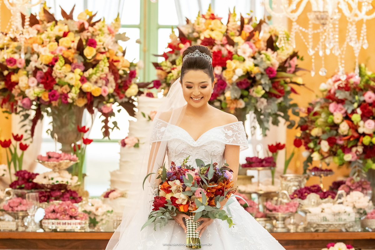 Que linda fotografia da noiva de olhos fechados, com a mesa de bolo ao fundo, muitas cores e felicidade estampada, belíssima fotografia de Sandro Andrade fotografo de casamentos de BSB.