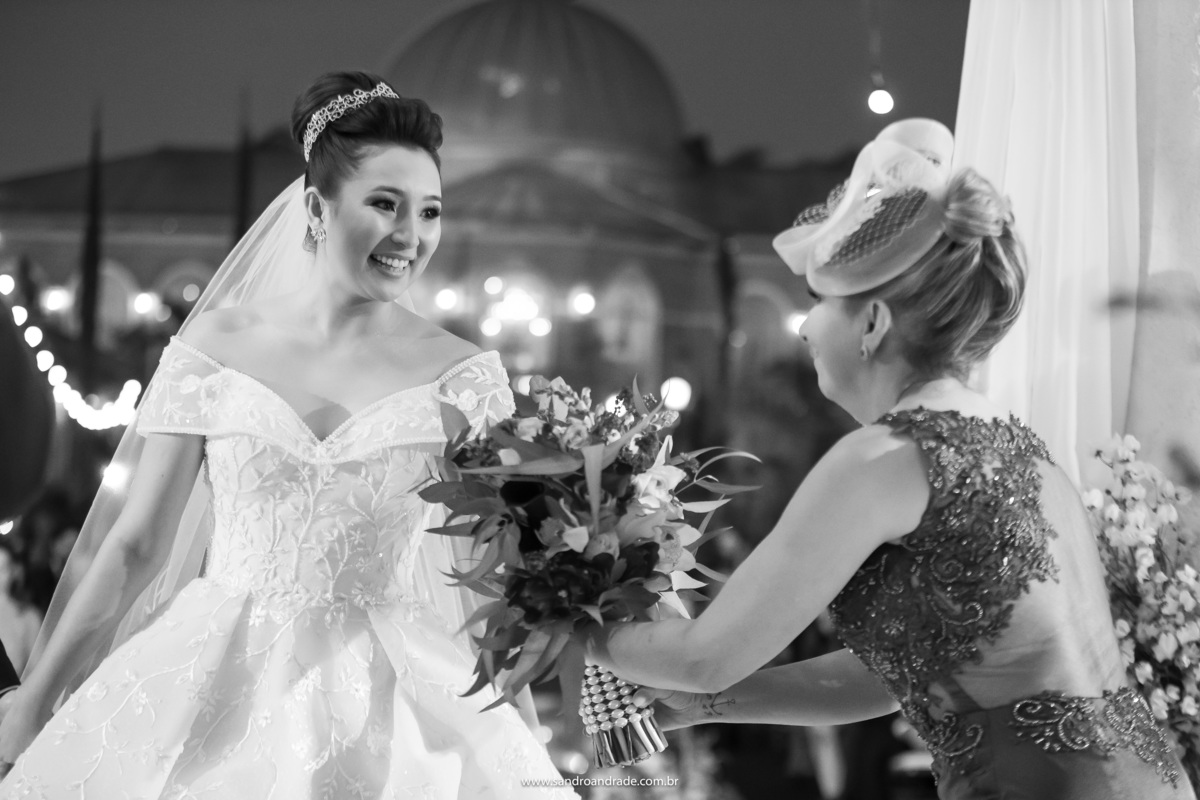 Um momento lindo, em preto e branco, o palazzo de fundo, Dany sorri e entrega seu lindo buque de noivas a sua mãe.