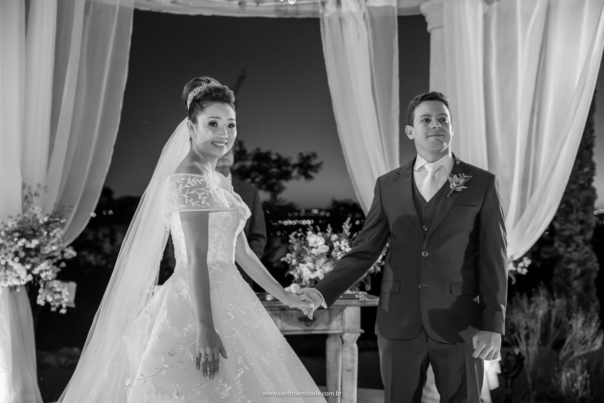 Dany e Murilo de mãos dadas olhando para a irmãzinha dela que vem trazendo as alianças.