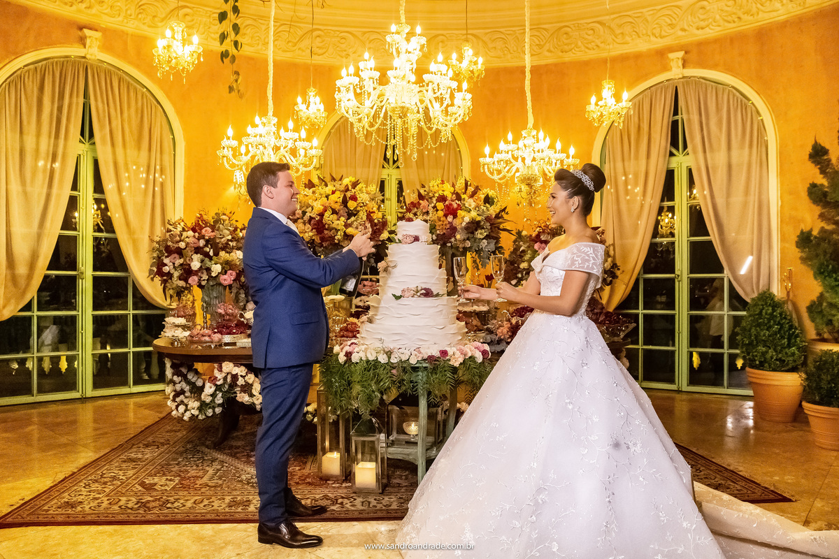 E la vai o brinde, de fundo uma linda mesa de bolo, muito bem decorada e iluminada.