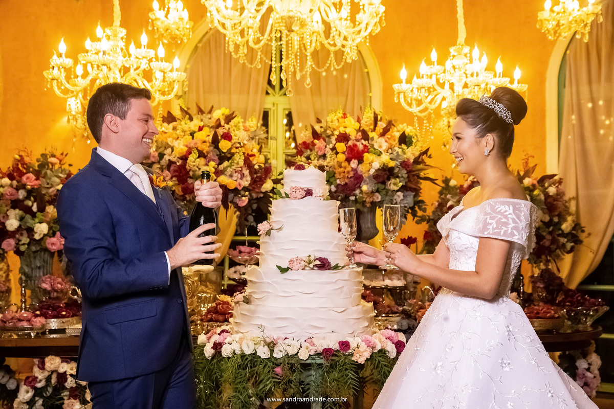 Eles estão muito felizes, nunca vi ninguém sorrir tanto para abrir o espumante, agora o noivo irá encher as taças.