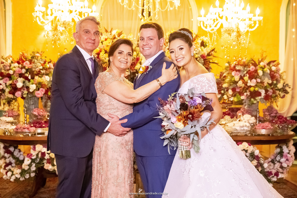 Fotografia tradicional  de casamento, o casal com os pais do noivo na mesa do bolo.