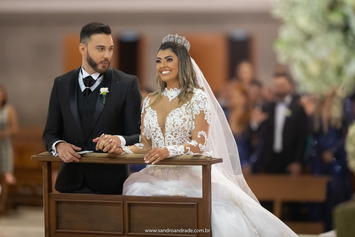 Ajoelhados, Wanessa sorri e Sandro a admira.