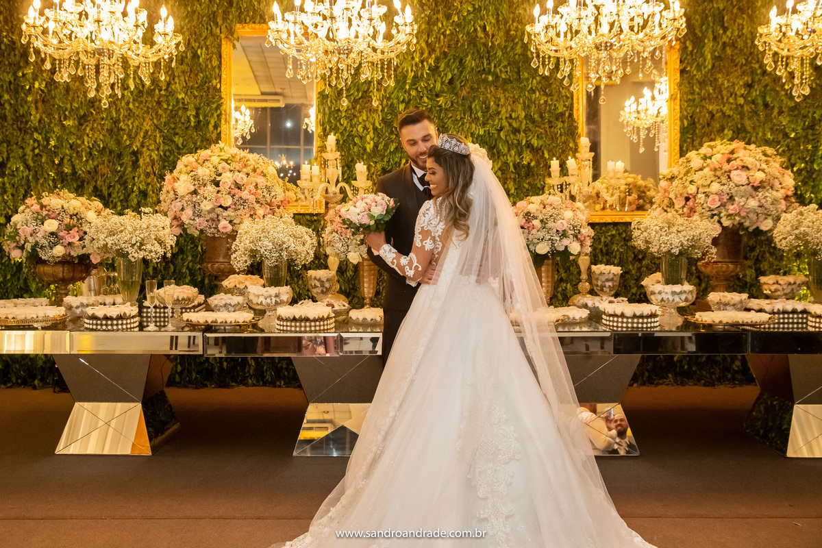 A noiva está de costas segurando o buquê e o noivo está de frente para ela.