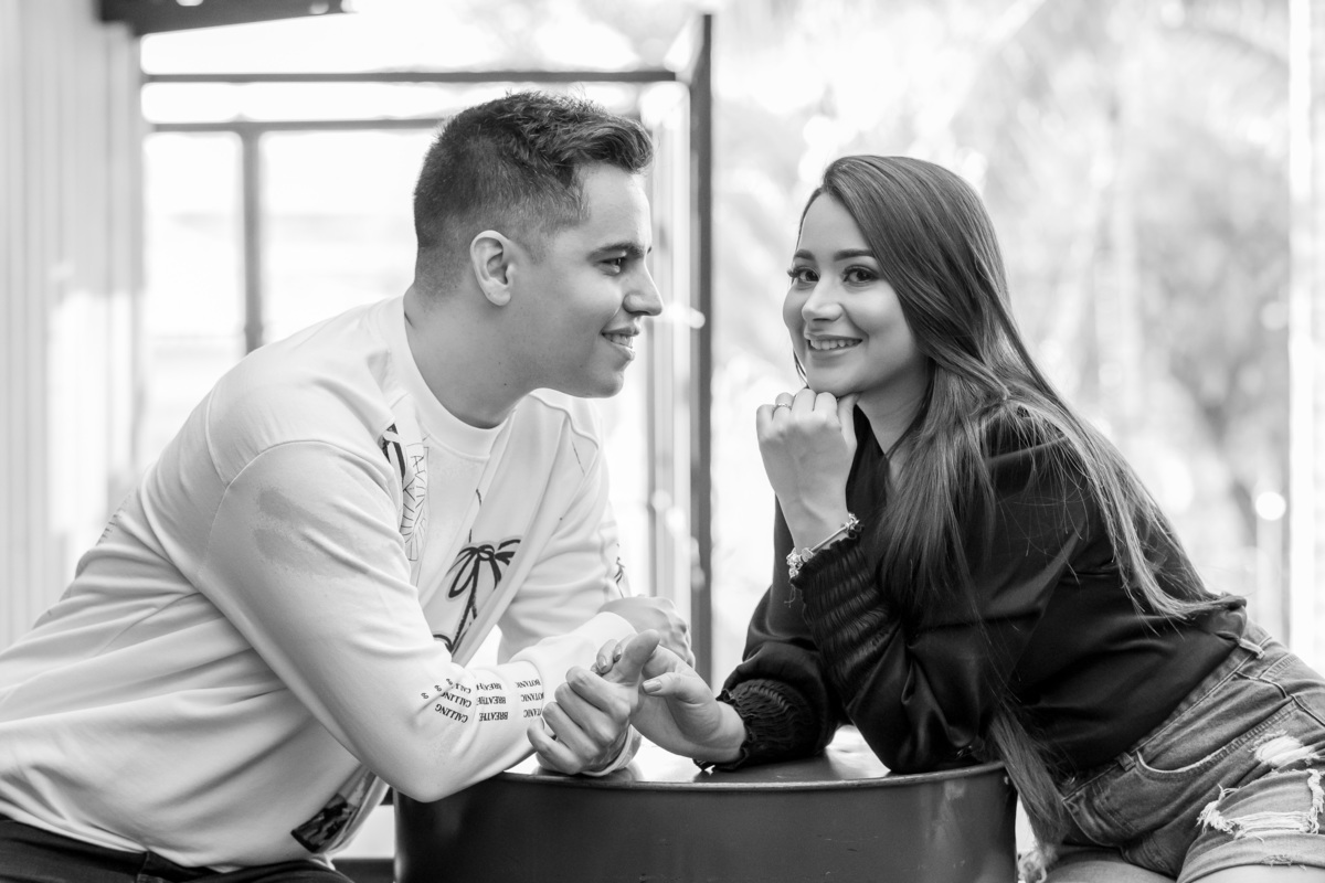 Linda fotografia do casal em preto e branco, digna de um lindo pôster, eles estão sentados na mesa de um gastro-bar de material reciclado, a mesa é um tonel, Paul apaixonado olha para Bárbara enquanto ela olha para as lentes do fotógrafo Sandro Andrade.