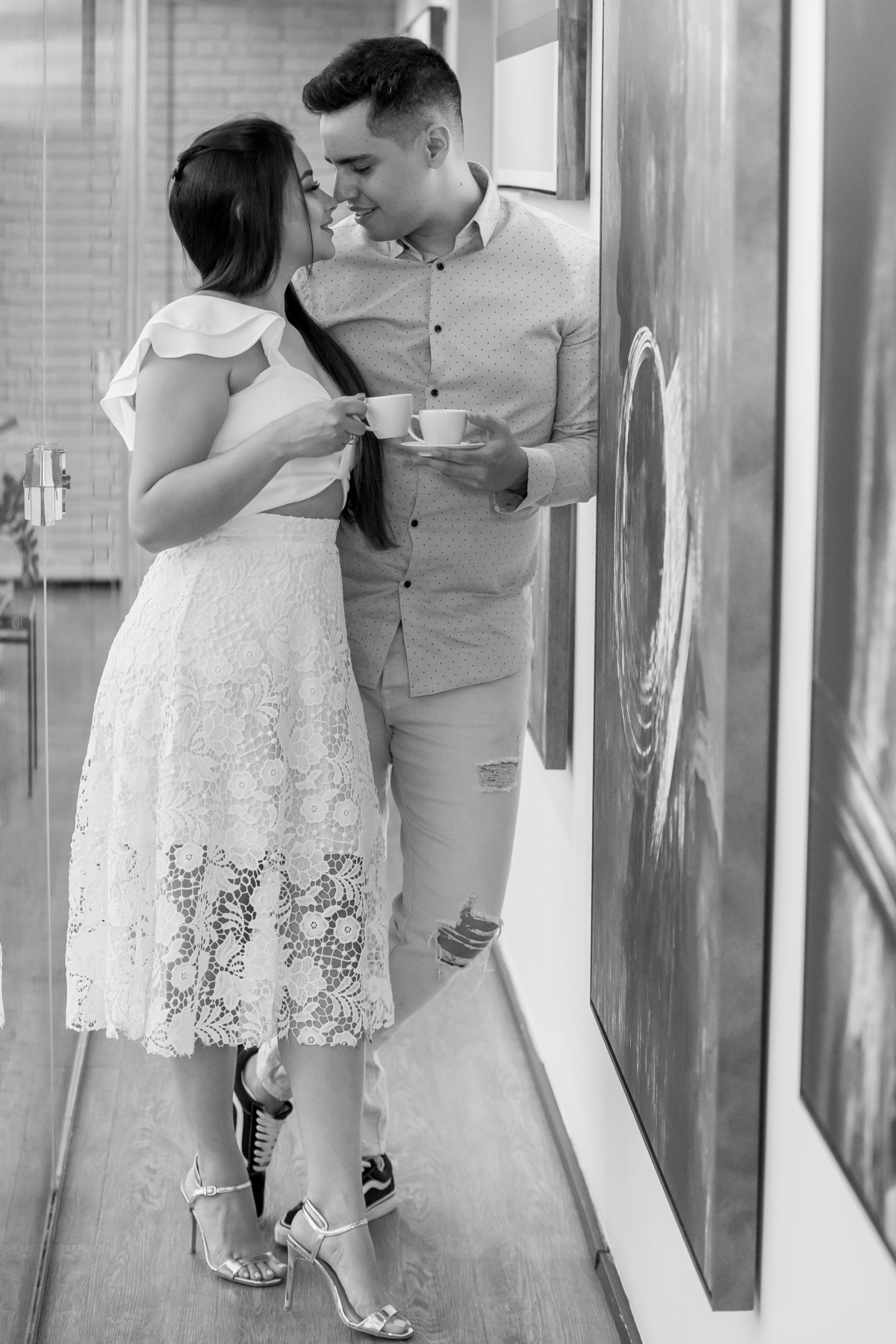 Curtindo arte e um bom café...eles estão de pé, recostado na parede da galeria, Paul abraça sua noiva, olho no olho e um brinde com café, tudo isso em um lindo preto e branco.