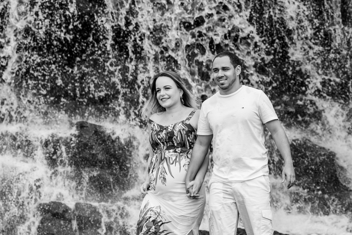 Retrato do casal de mãos dadas caminhando na cachoeira.