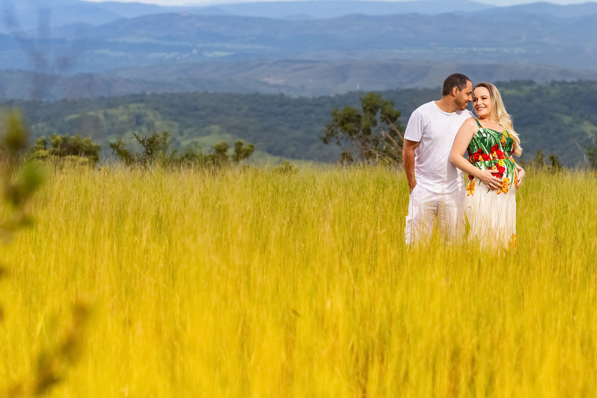 Renato e Sarah estão no mesmo local da foto anterior, abraçados, se olhando e sorrindo apaixonados.