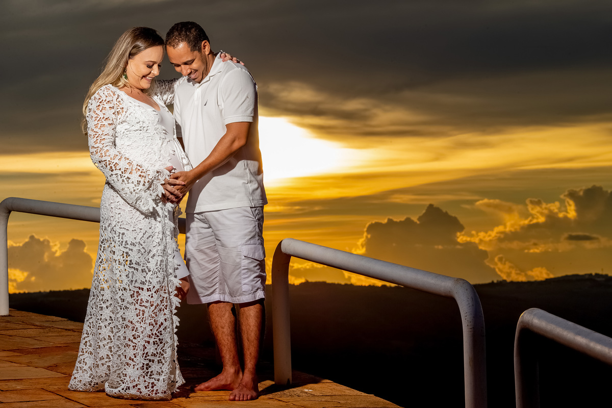Uma linda fotografia colorida, o casal olhando para a barriga gestando a Gigi, com um sorriso contagiante e felizes.