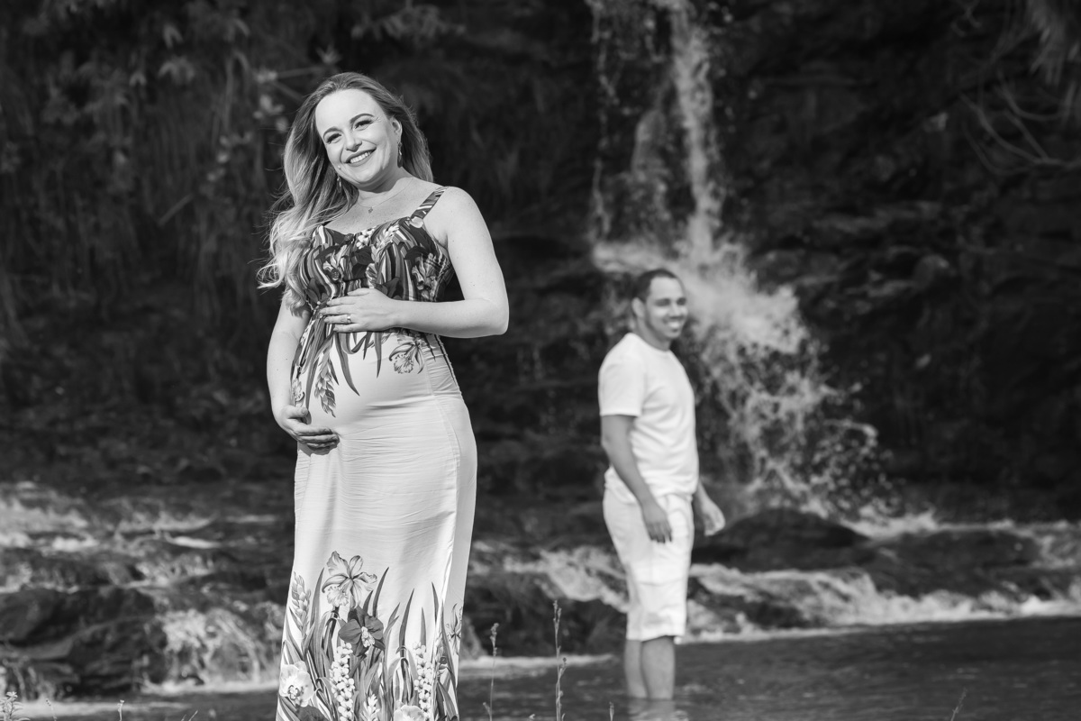 Esse lindo ensaio foi realizado no Paraíso na Terra em Brazlandia, foto em preto e branco com Sarah em primeiro plano sorrindo com as mãos na barriga e Renata na cachoeira ao fundo.