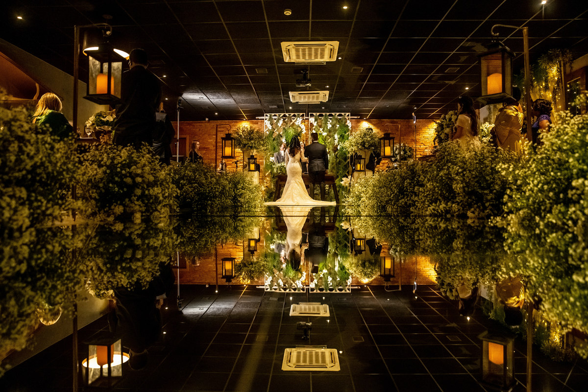 Perfeiçãoooo...Que maravilhosidade esta fotografia colorida! Os noivos estão de costas e além de toda a decoração nas laterais, tem um tapete espelhado refletindo a decoração e o casal. Fotografia do fotógrafo premiado Sandro Andrade.