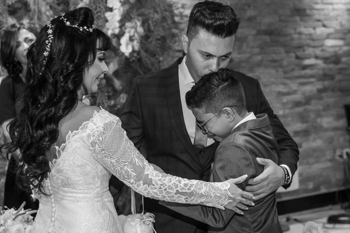 Gustavo abraça seu filho do coração e o acalma com um beijo na cabeça enquanto a mãe dele, o acaricia no braço. Lindo momento!