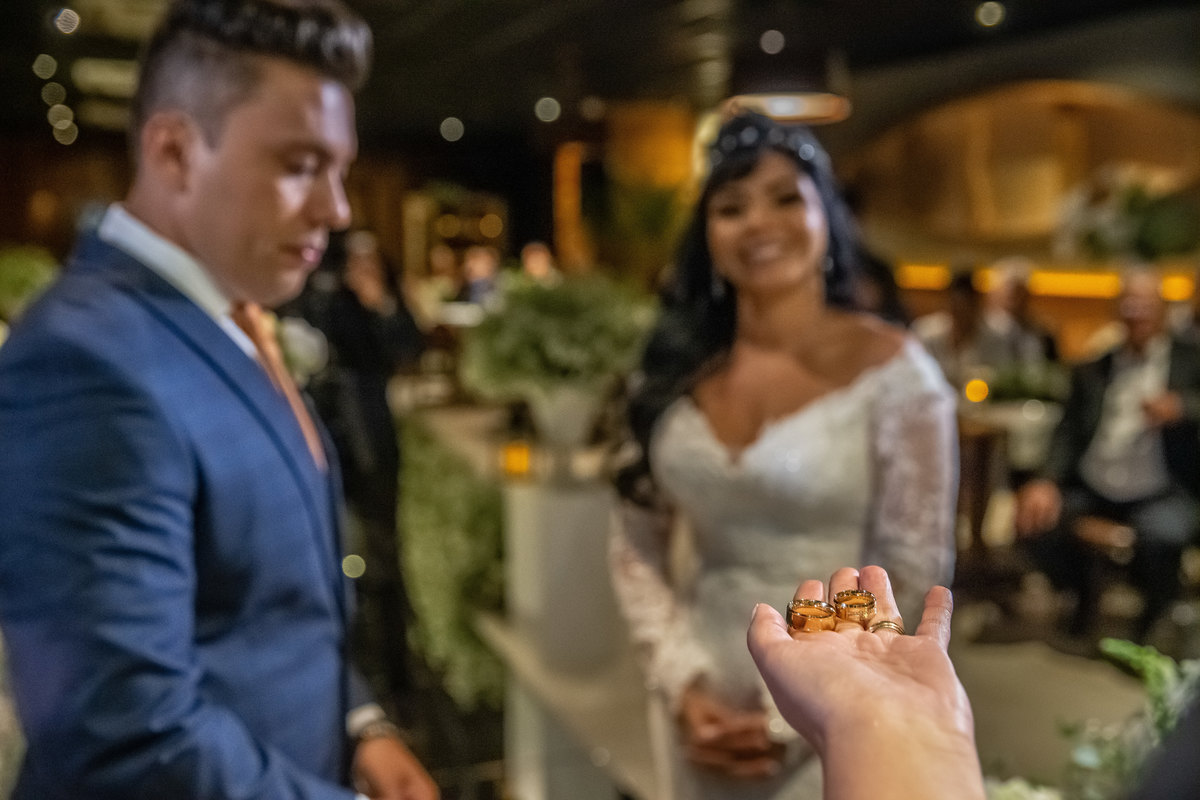 E que alianças, muito lindas! Os noivos sorriem ao fundo, desfocados, ouvindo os comentários da pastora sobre as alianças na mão dela, rsrsrs.  