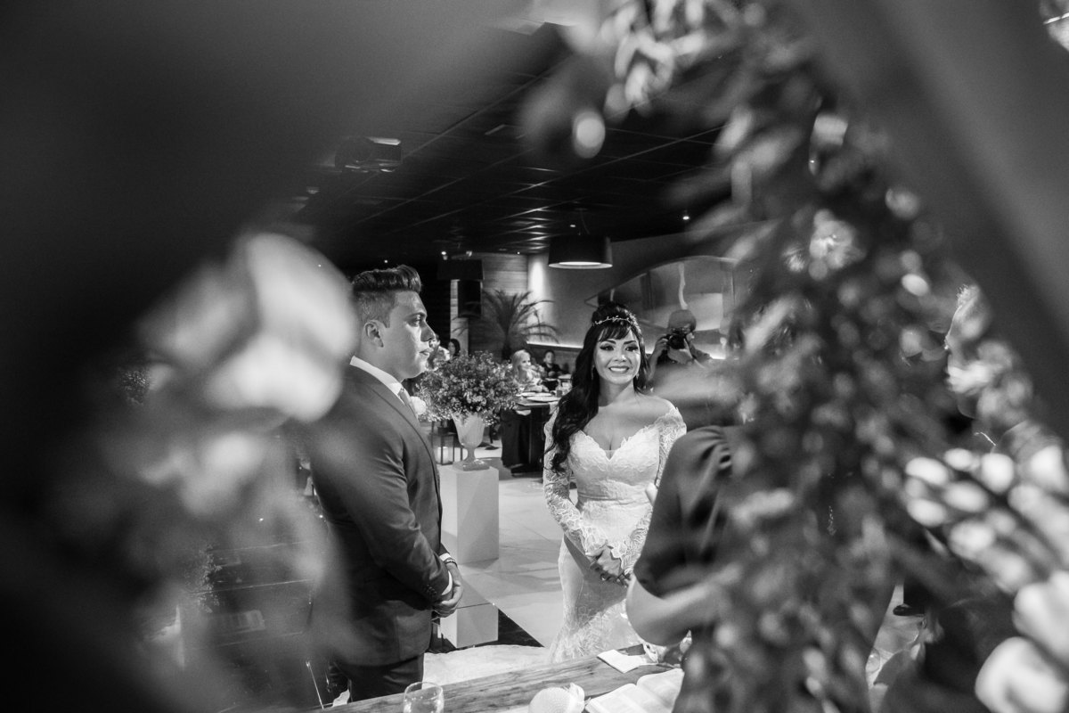 Pura arte! Fotografia preto e branco, artistica. Os noivos entre a decoração do altar da cerimonia, um triângulo e eles ao fundo.