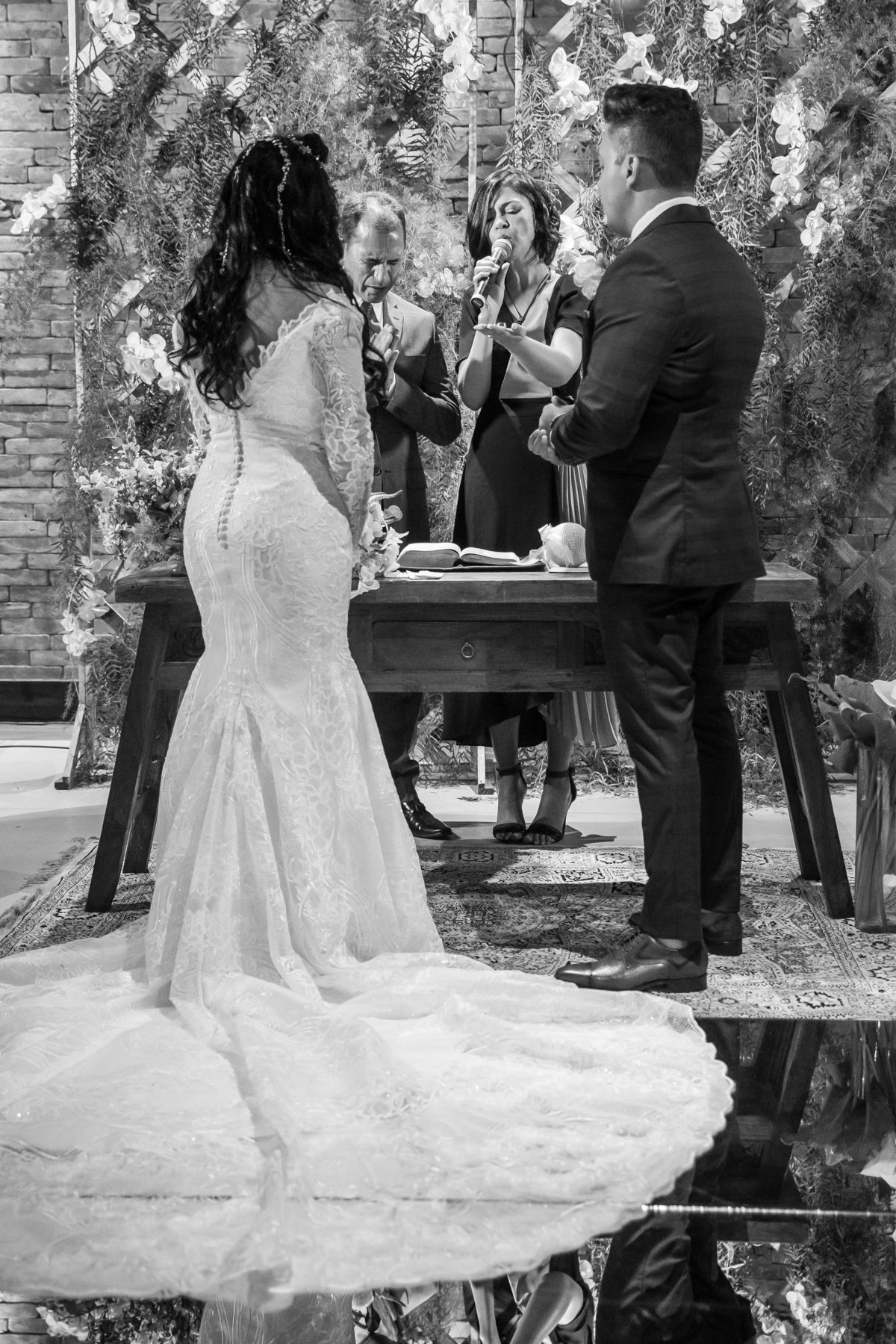 A benção das alianças...o casal está de costas e os pastores atras deles, o pastor orando e a pastora com as alianças na mão.