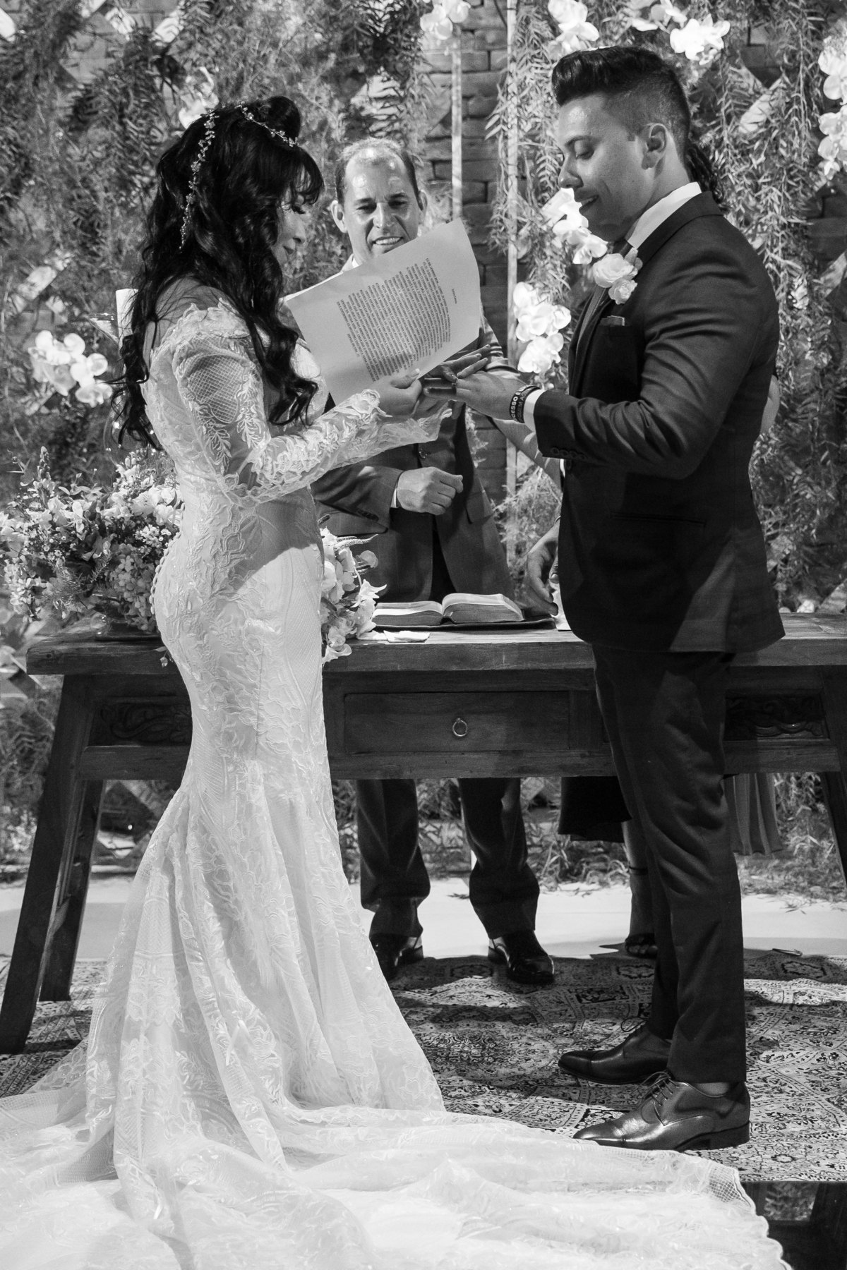 Ainda colocando a aliança em Gustavo, um retrato de corpo inteiro do casal em preto e branco.