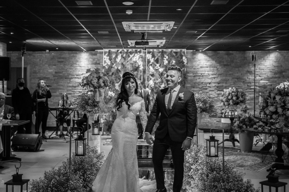 Felizes eles distribuem sorriso para os convidados durante a saída e Cássia comemora erguendo seu lindo buquê de noiva.