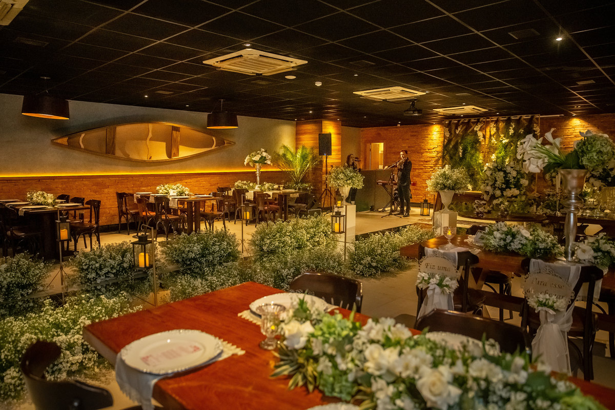 Uma fotografia do local da cerimonia com as mesas ao fundo e a mesa dos noivos a frente.