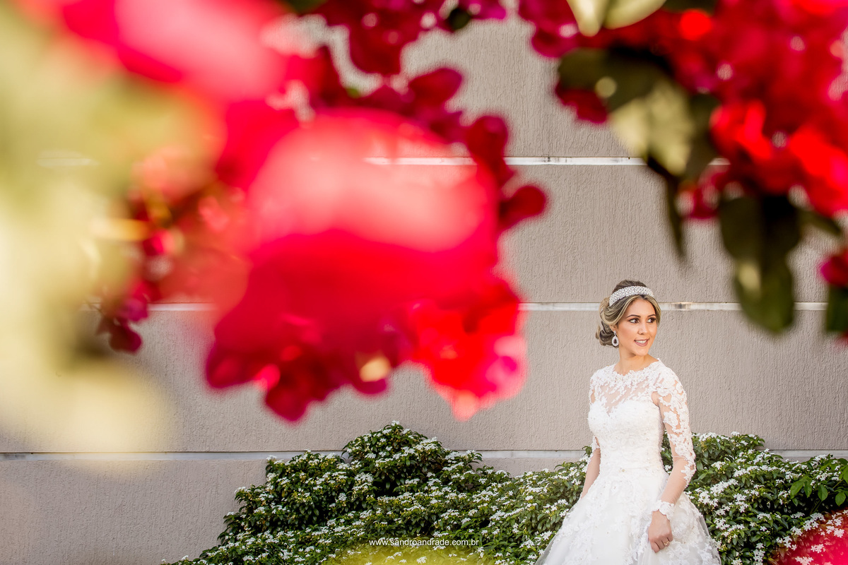 A noiva sorrindo e no meio do jardim, com as flores da Bougainville emoldurando ela.
