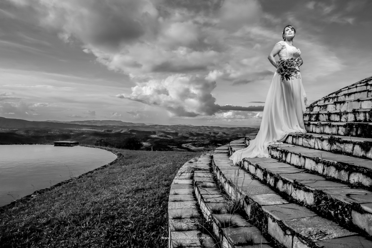 Em preto e branco, a noiva está no meio da escada com seu lindo vestido branco do atelier Maria Virginia, mão na cintura e um buque maravilhoso da Joyce Albuquerque cerimonialista.