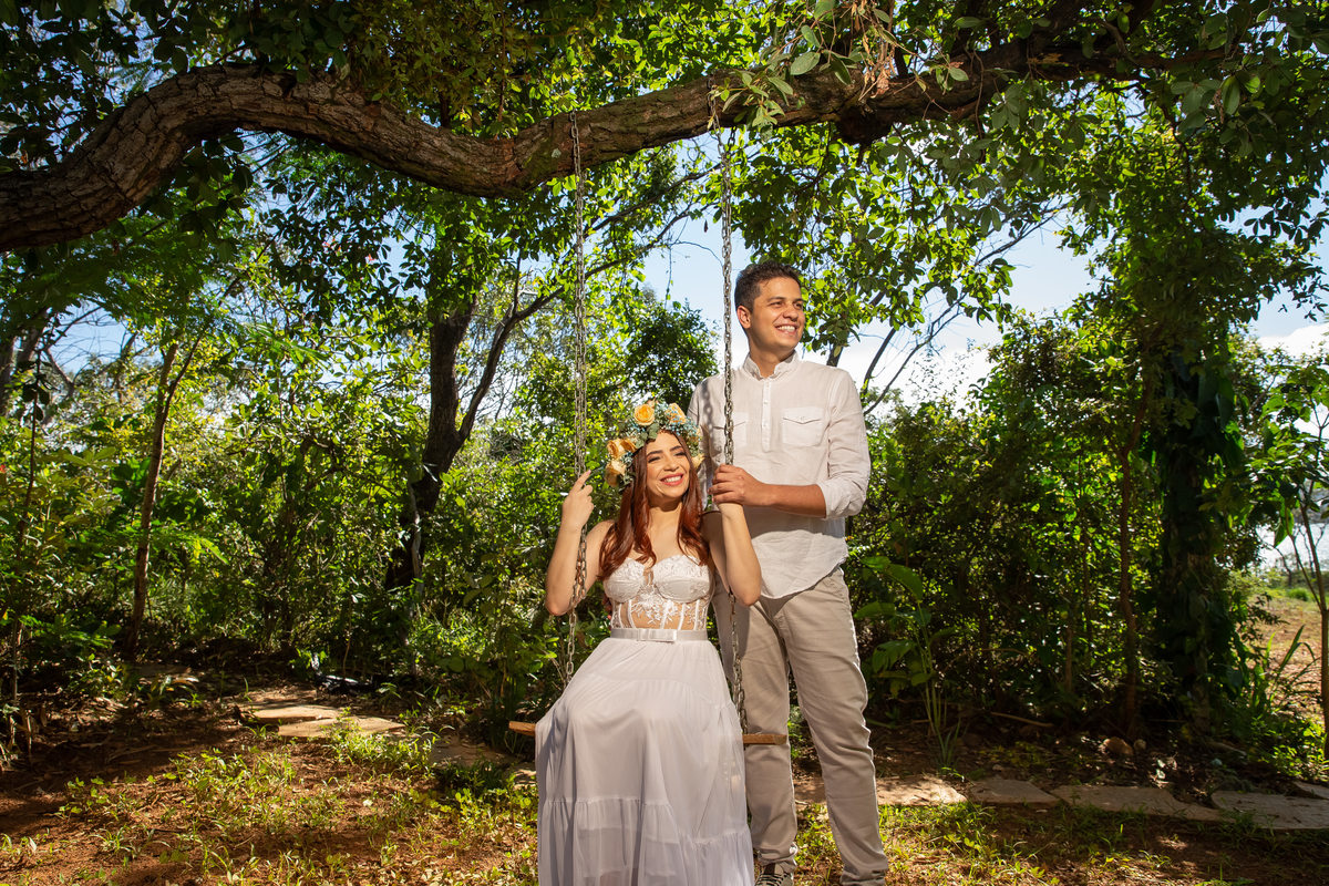 Sentada no balanço da Villa Giardini, Jessy sorri e Bruce esta em pé na lateral dela, ambos sorriem olhando a luz artificial, uma das especialidades de Sandro Andrade, um artista da fotografia de casamentos no Brasil.