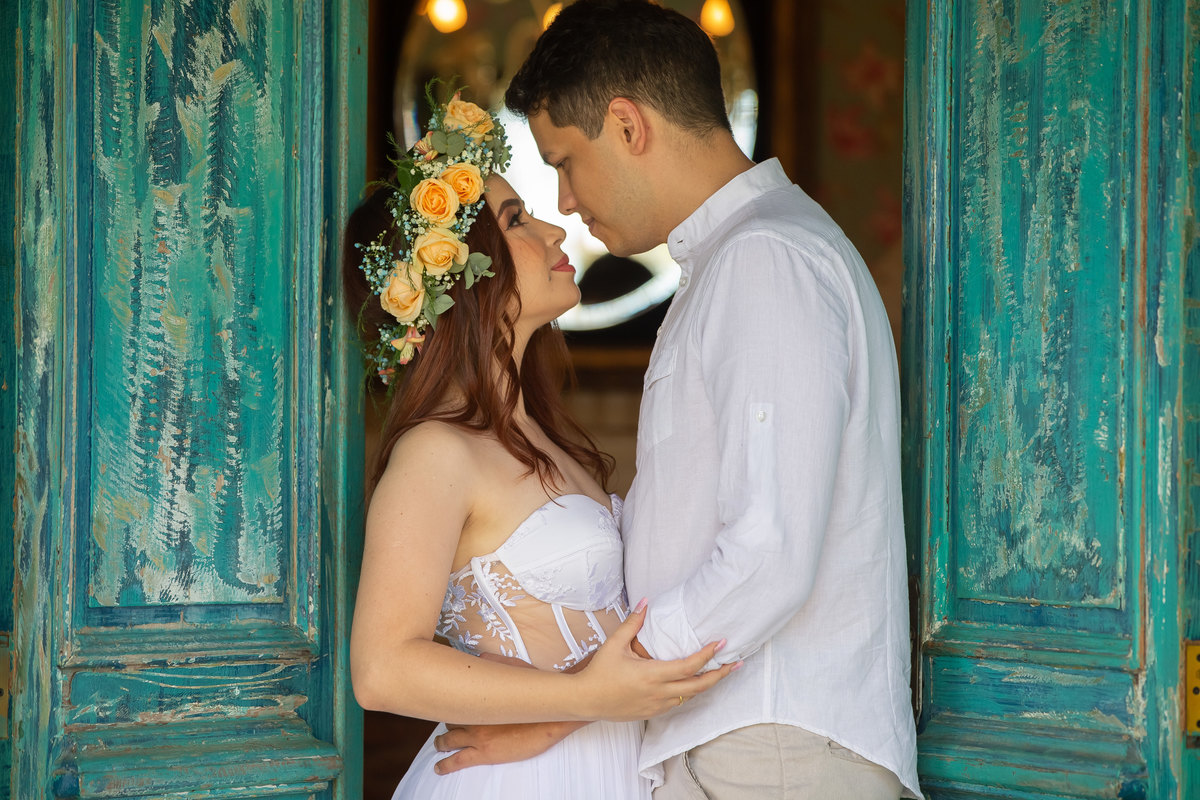 Sandro Andrade é um fotógrafo famoso por seus clicks únicos e de cores vibrantes. O casal está na porta do quarto da noiva, os dois encostados na porta de cor verde e um olhar conquistador.