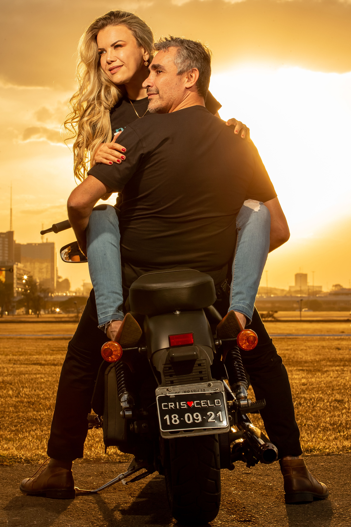 Uma linda imagem, com um pôr do sol maravilhoso e o casal olhando lateral.