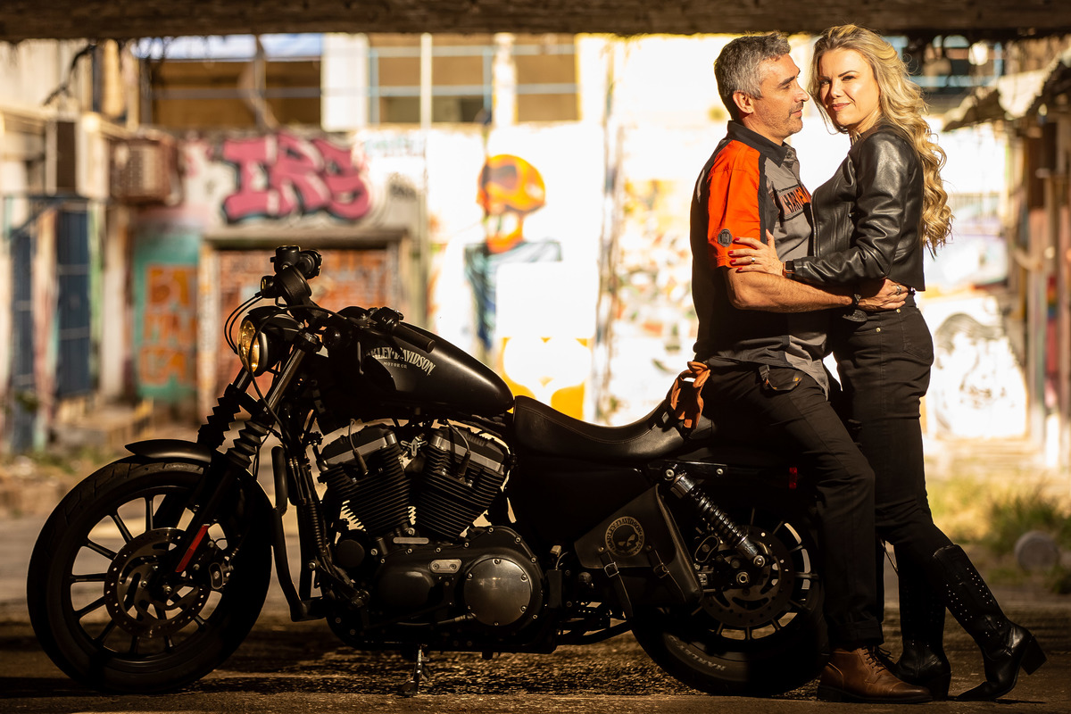 Em pé, recostados na moto, de frente um para o outro, Marcelo olhando para sua linda noiva e ela olhando para as lentes de seu fotógrafo, artista desta linda coleção de fotos maravilindas.