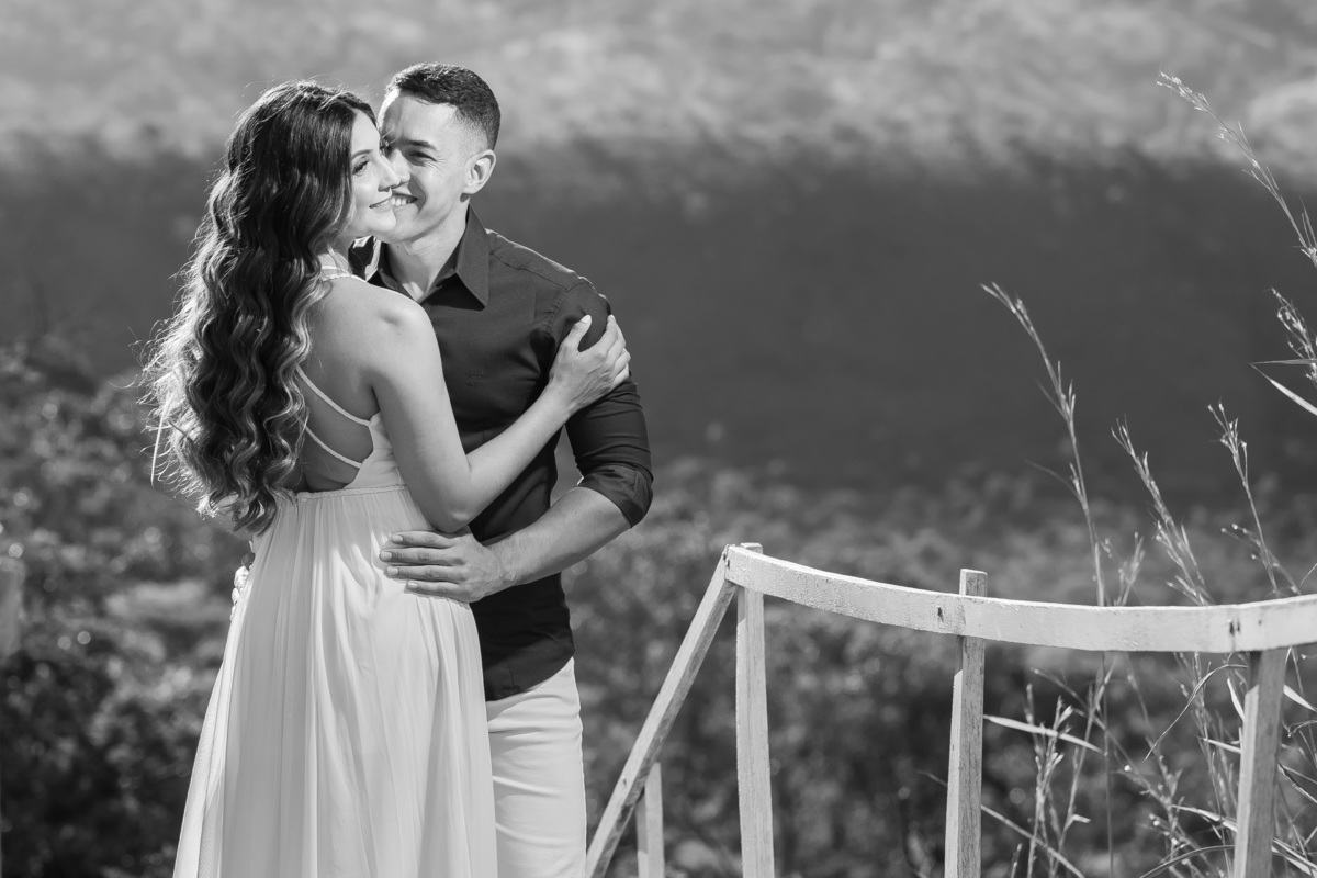 Em preto e branco Dani e Ítalo sorriem, em um lindo retrato, ela está de costas para seu fotografo Sandro Andrade fotógrafo de casamentos e Ítalo está de frente para ela.