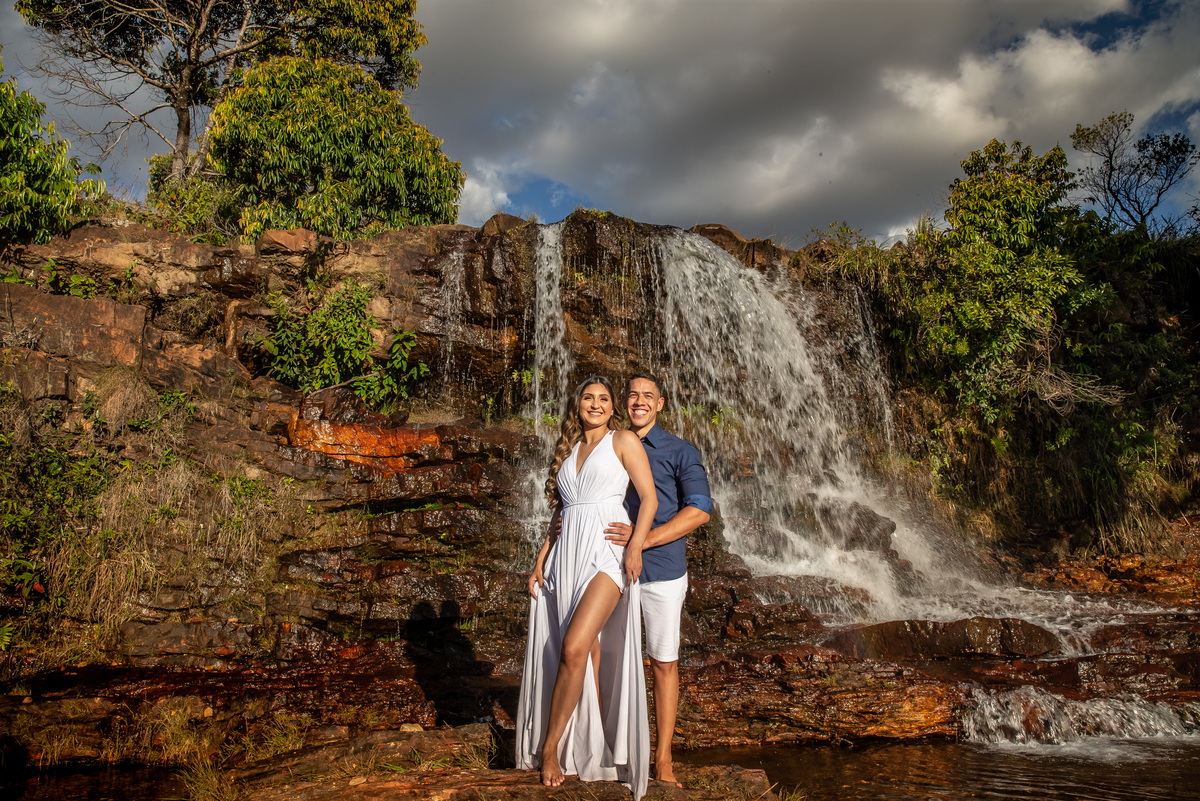 Desta vez com toda a cachoeira Mumunhas, o céu cheio de nuvens e árvores nas laterais, o casal está a frente e olha para as lentes de Sandro sorrindo descontraídos e felizes.
