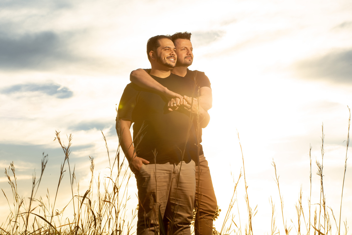 Mais um retrato do casal, o Jorge abraça o Victor por trás e bem descontraídos observam o serrado, ao fundo um lindo céu com nuvens em tons de azul e amarelo clarinhos.