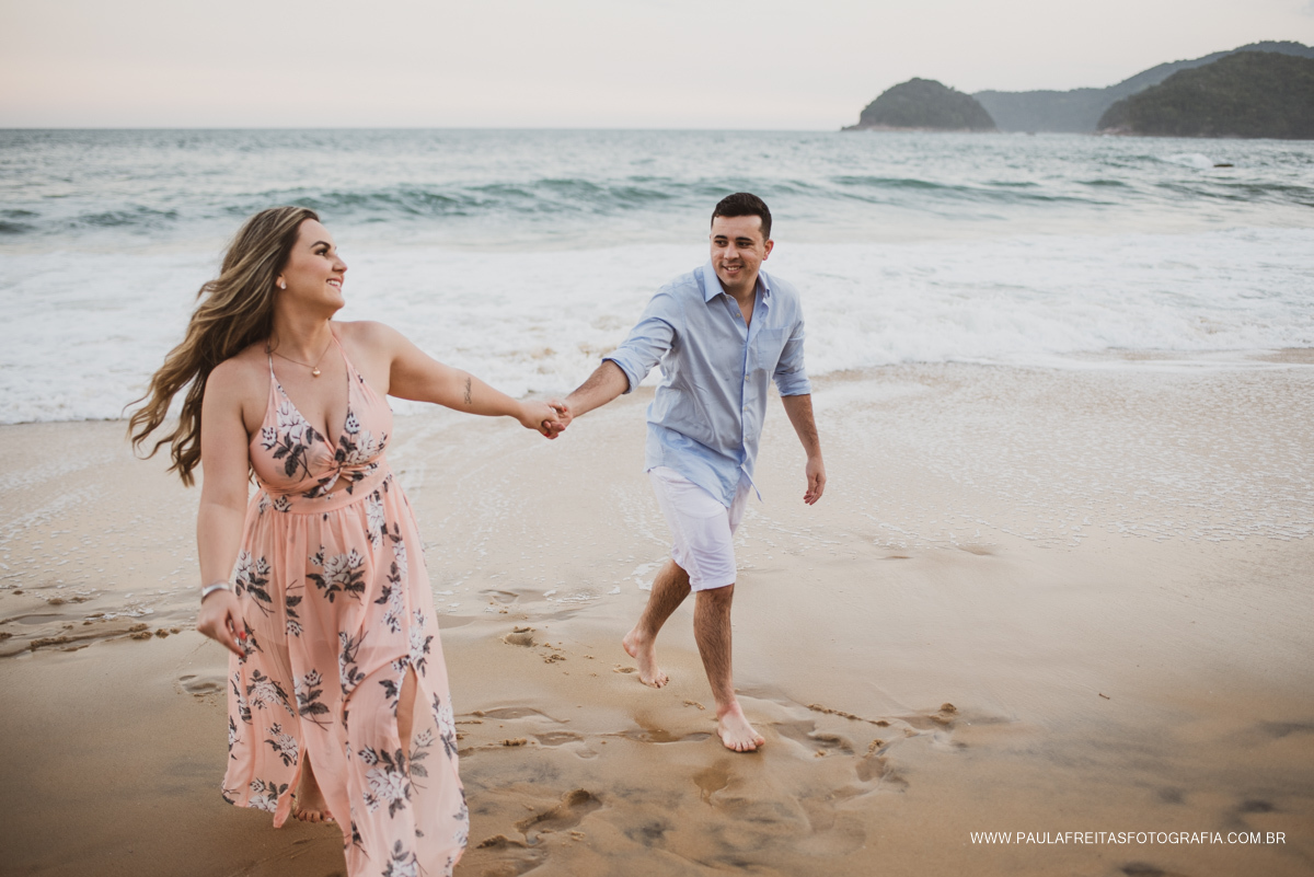Noivos correndo na areia em ensaio para casamento