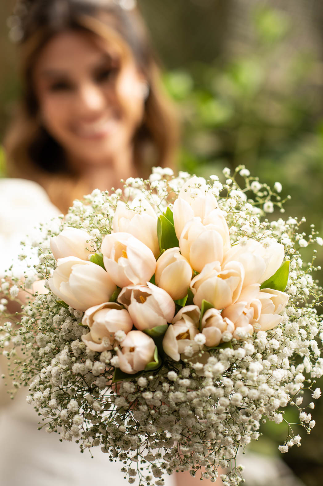 Fotografia de bouquet com noiva ao fundo desfocada.