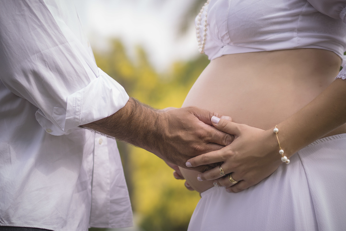 mãos no barrigão da gestante no click da fotógrafa....