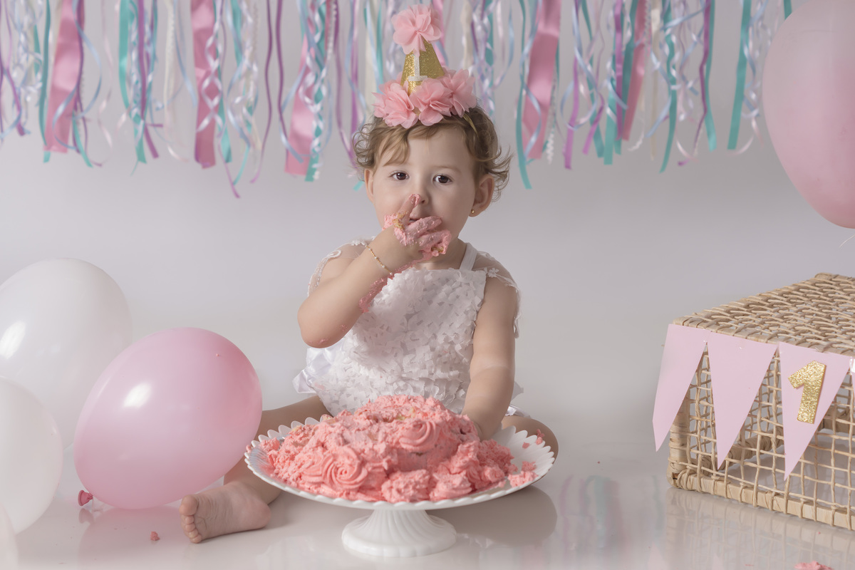 menina comendo bolo rosa