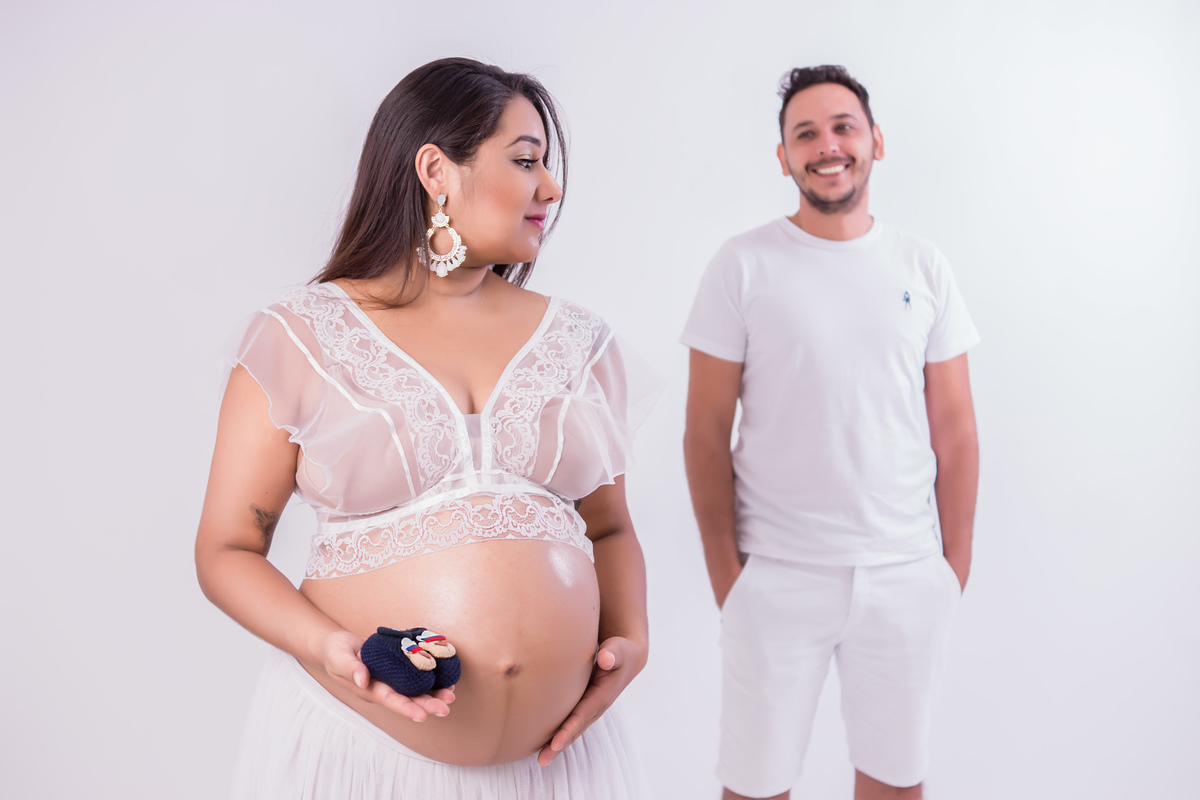 pai e gestante de branco segurando sapatinho