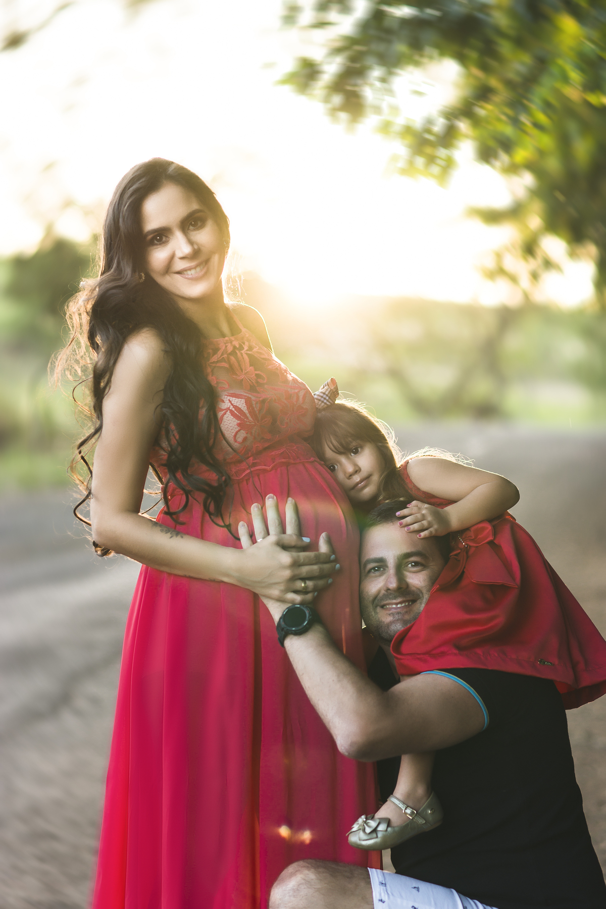 grávida com marido e filha no pôr do sol