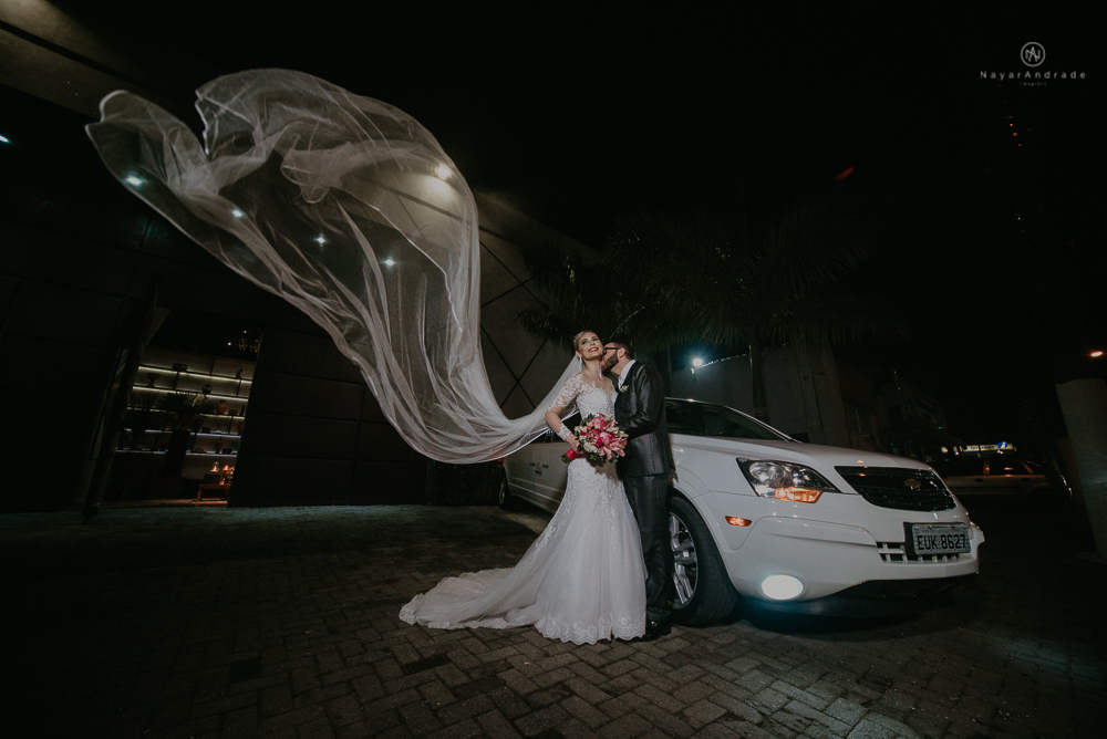 Fotos externas de casamento feitas no salão atmosfera no guarujá. NOiva com véu voando e limosine branca.