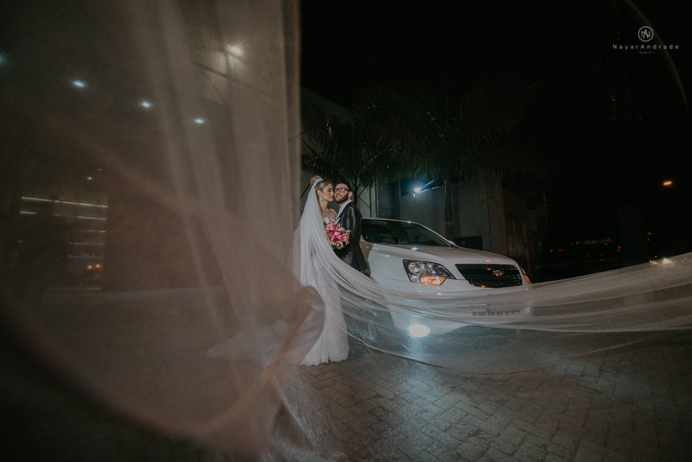 Fotos externas de casamento feitas no salão atmosfera no guarujá. NOiva com véu voando e limosine branca.