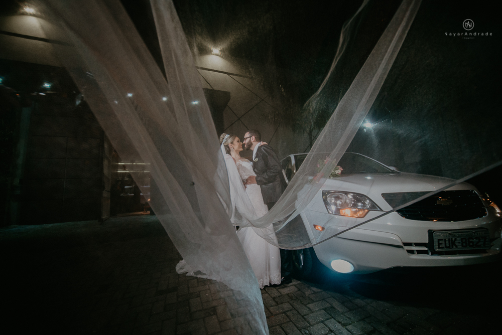 Fotos externas de casamento feitas no salão atmosfera no guarujá. NOiva com véu voando e limosine branca.