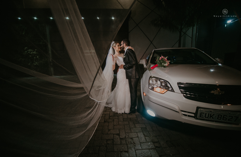 Fotos externas de casamento feitas no salão atmosfera no guarujá. NOiva com véu voando e limosine branca.
